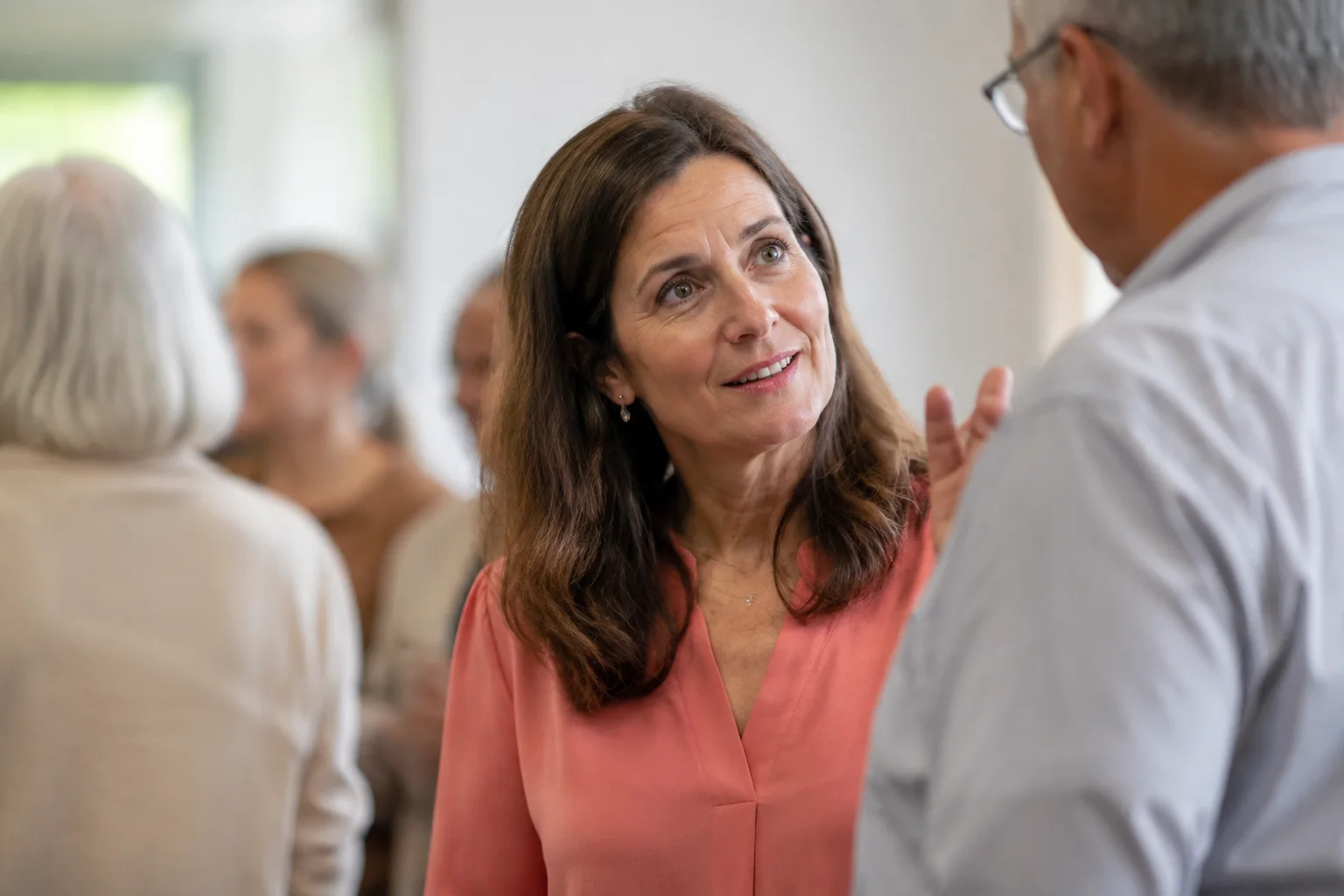 A woman listening closely as another person introduces themselves