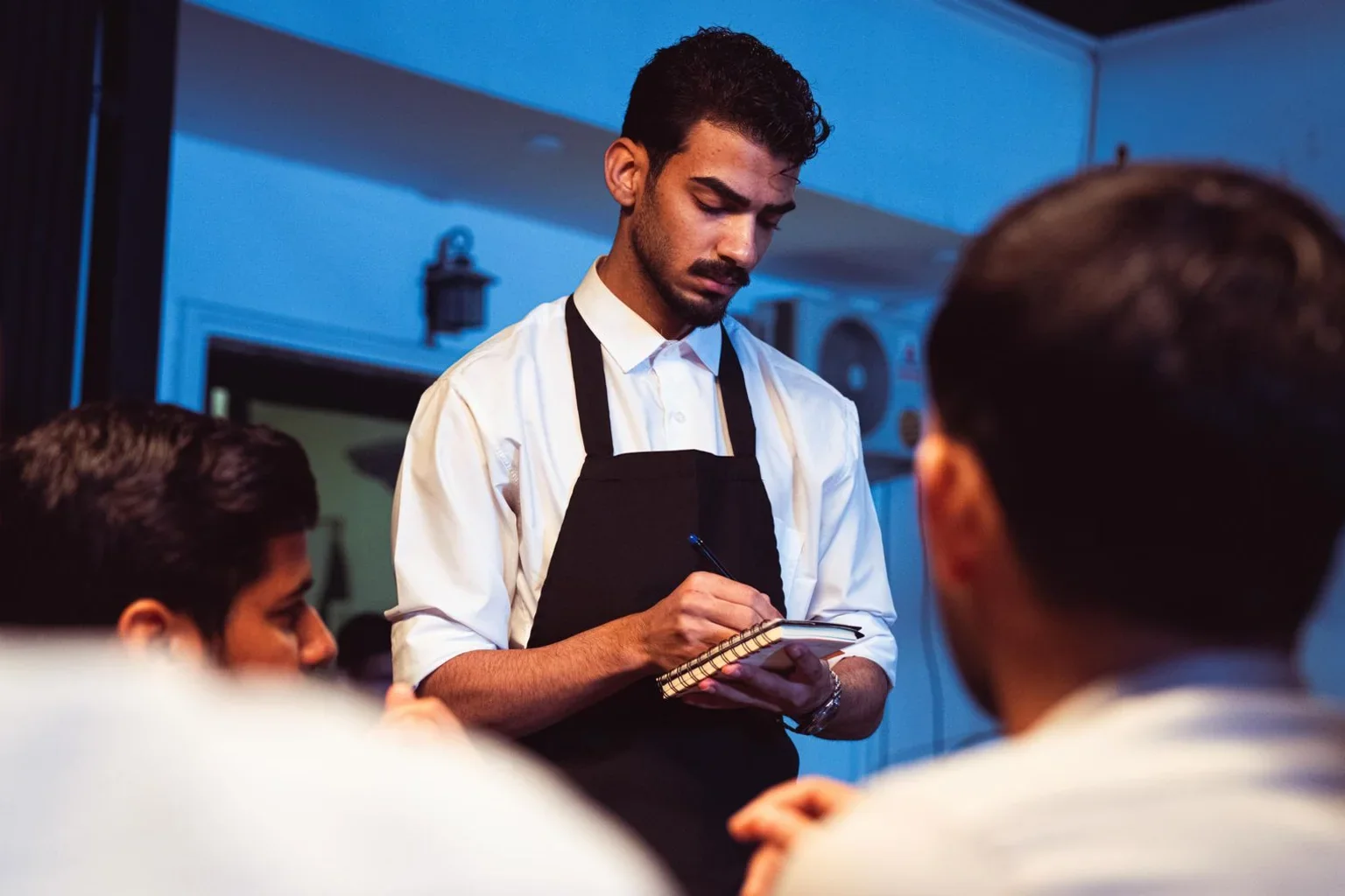 A waiter writing down a restaurant guest’s order