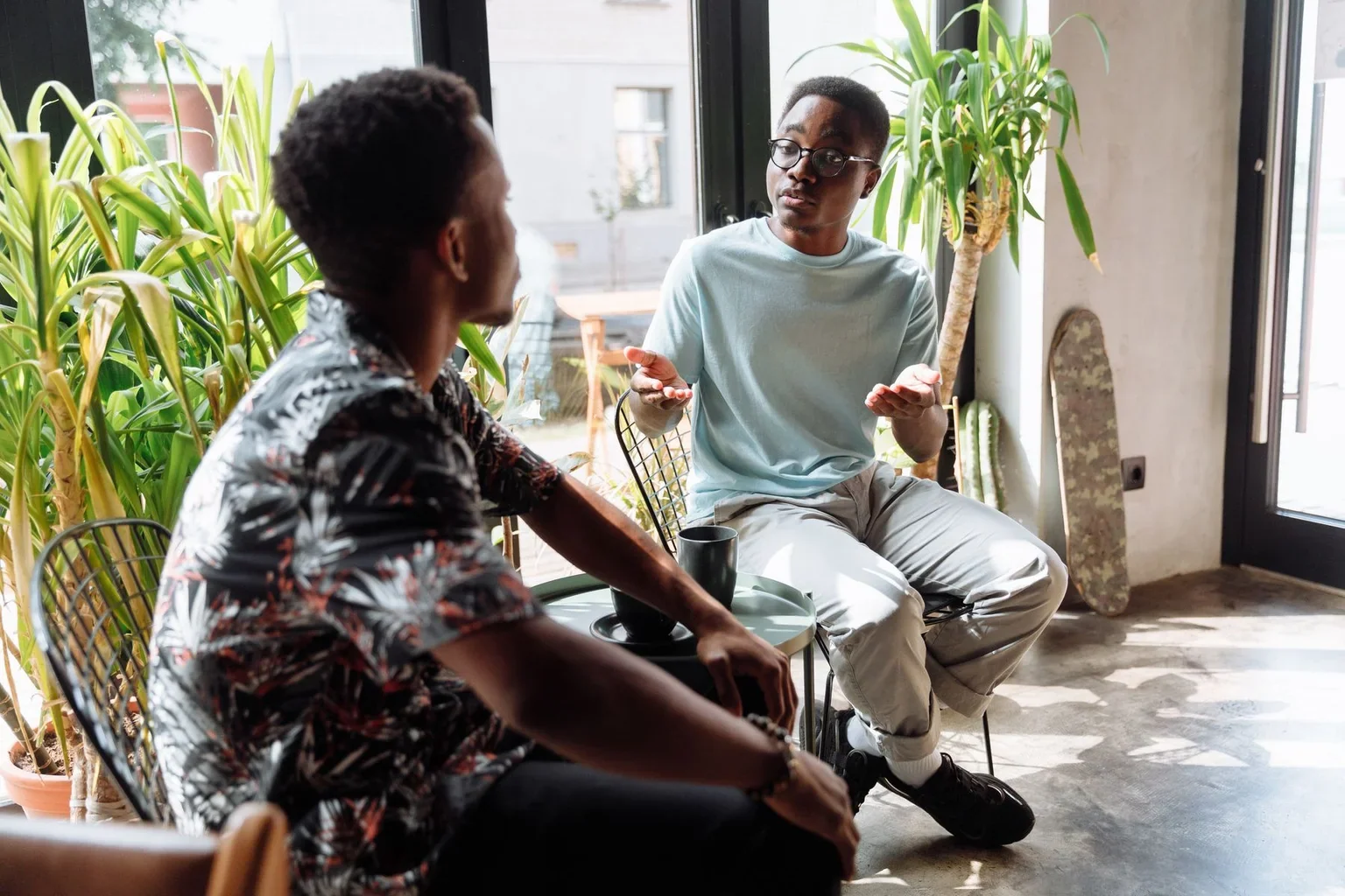 Two people talking in armchairs beside a window