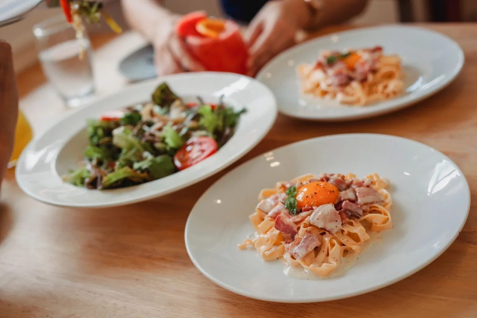 Pasta dishes with a separate bowl of salad on a restaurant table