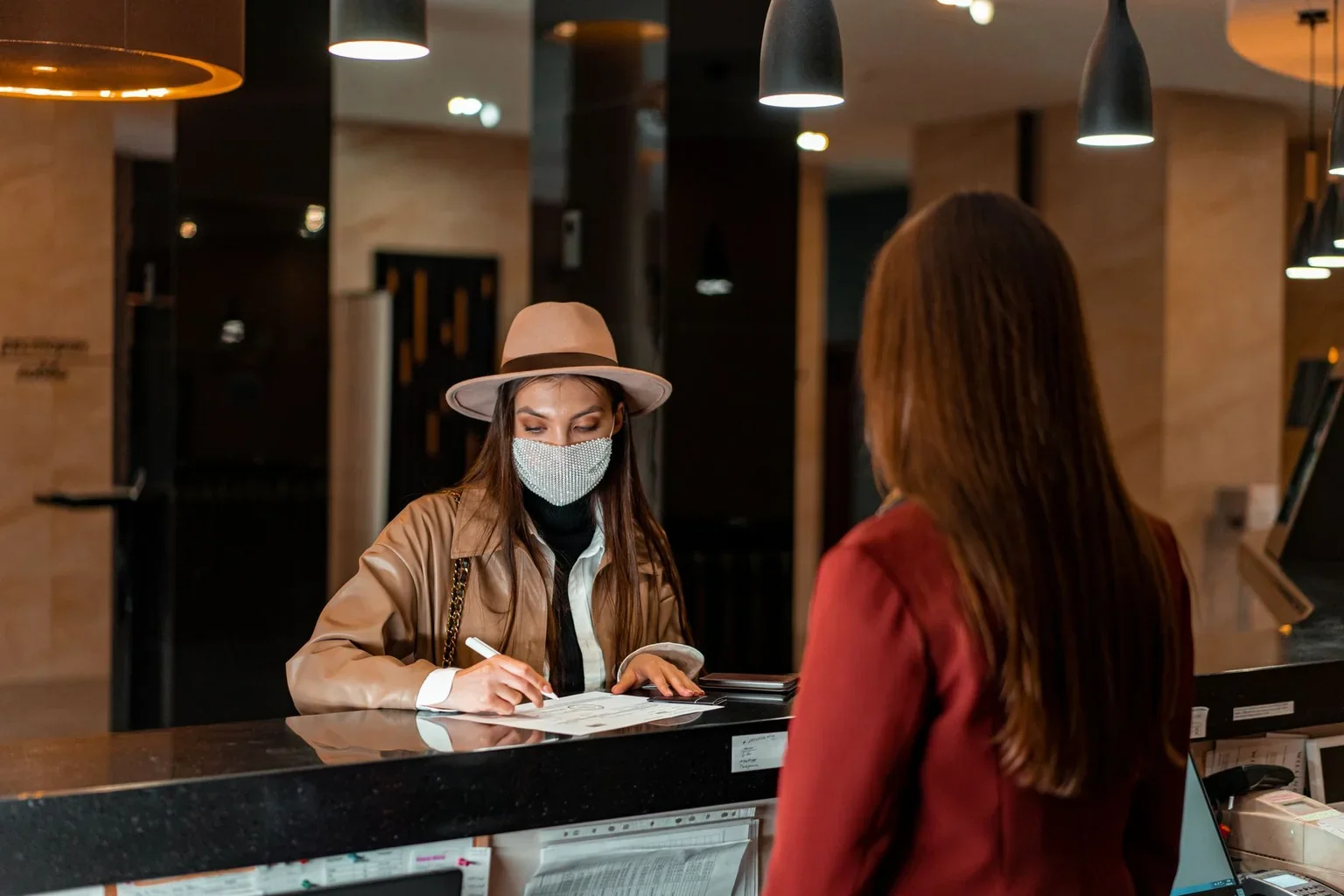 A guest speaking with a receptionist across a hotel counter