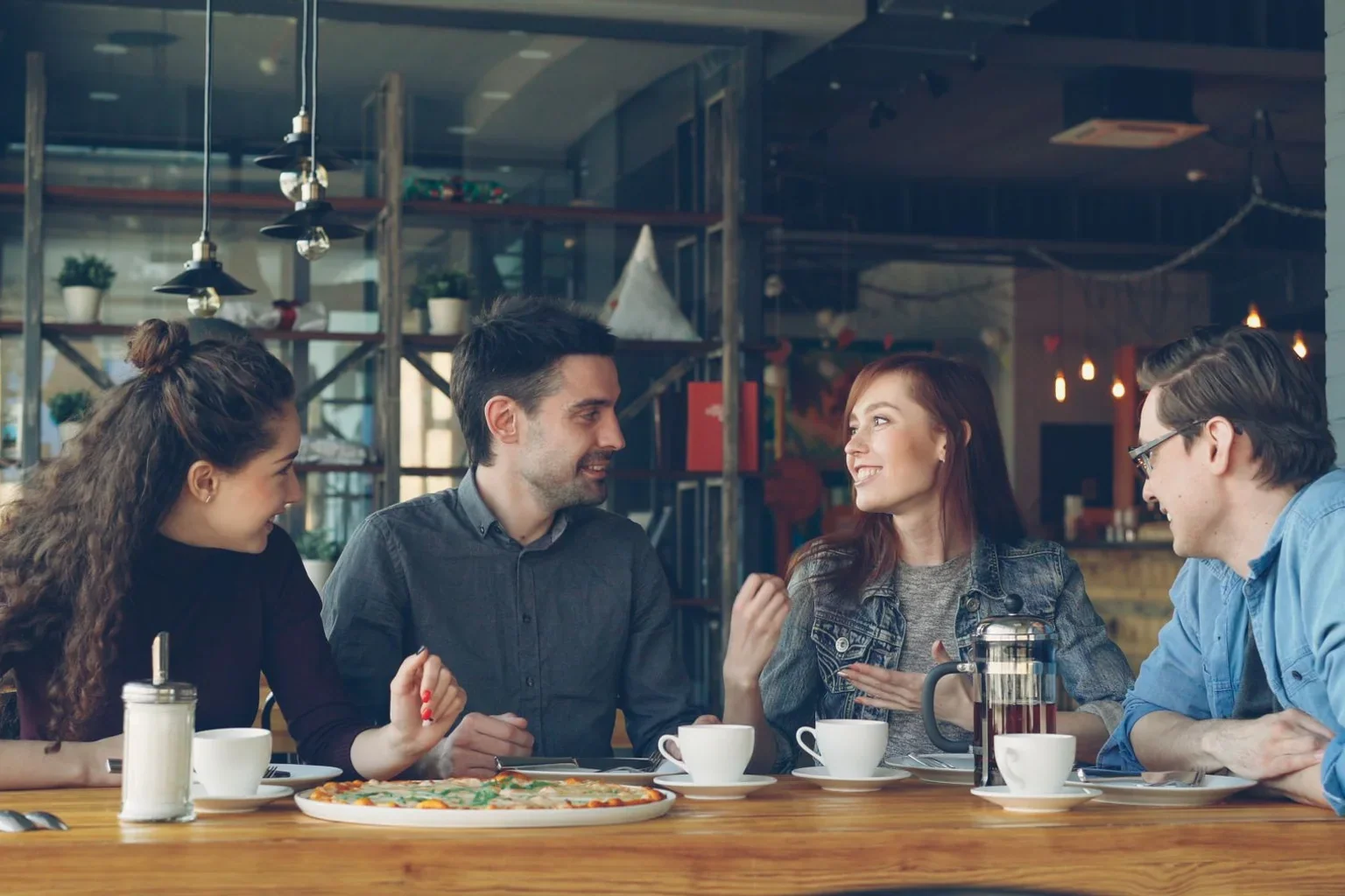 Four friends sharing food and conversation at a café