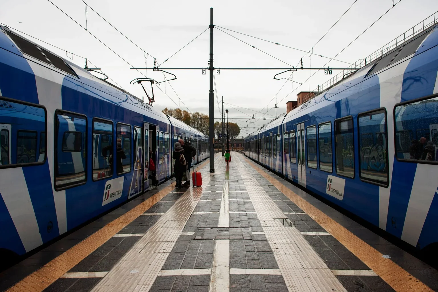 Passenger trains on both sides of an Italian station platform