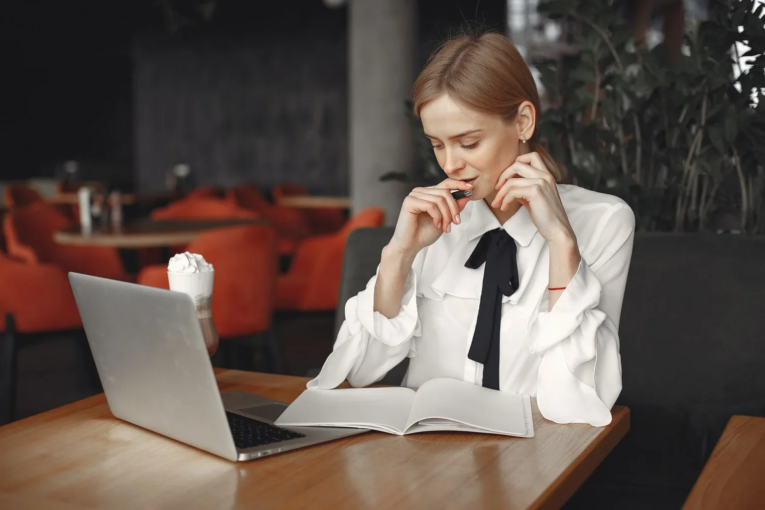 A woman planning at a table with a notebook and laptop
