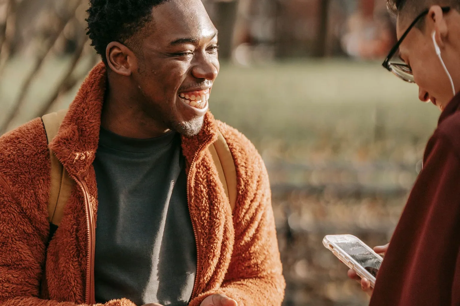 Two friends using phones during a park visit